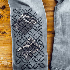 Gray jeans with decorative cut-out pattern on a wooden surface